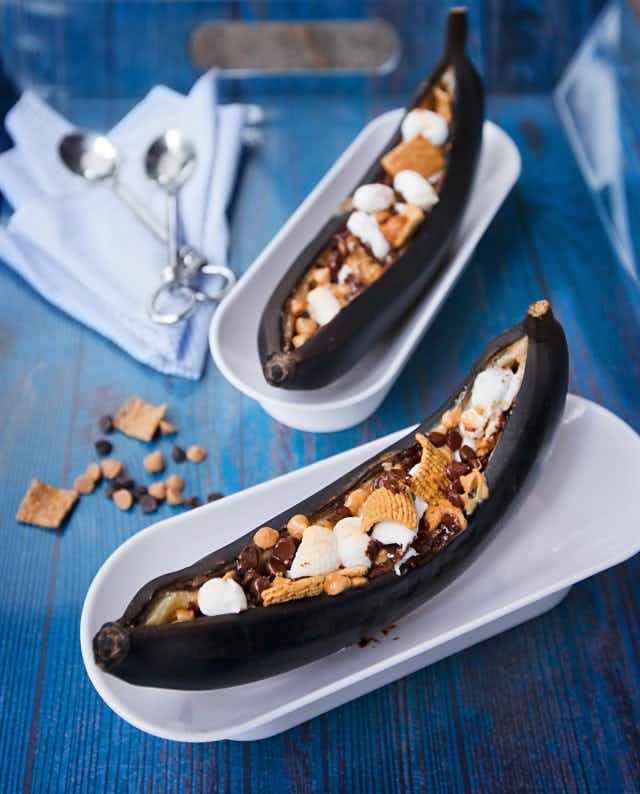 banana boat desserts on a plate with marshmallow, cereal and chocolate chips