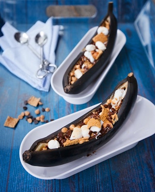banana boat desserts on a plate with marshmallow, cereal and chocolate chips