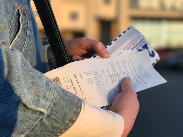 a woman holding a bed bath and beyond coupon and a bed bath and beyond receipt in her hands