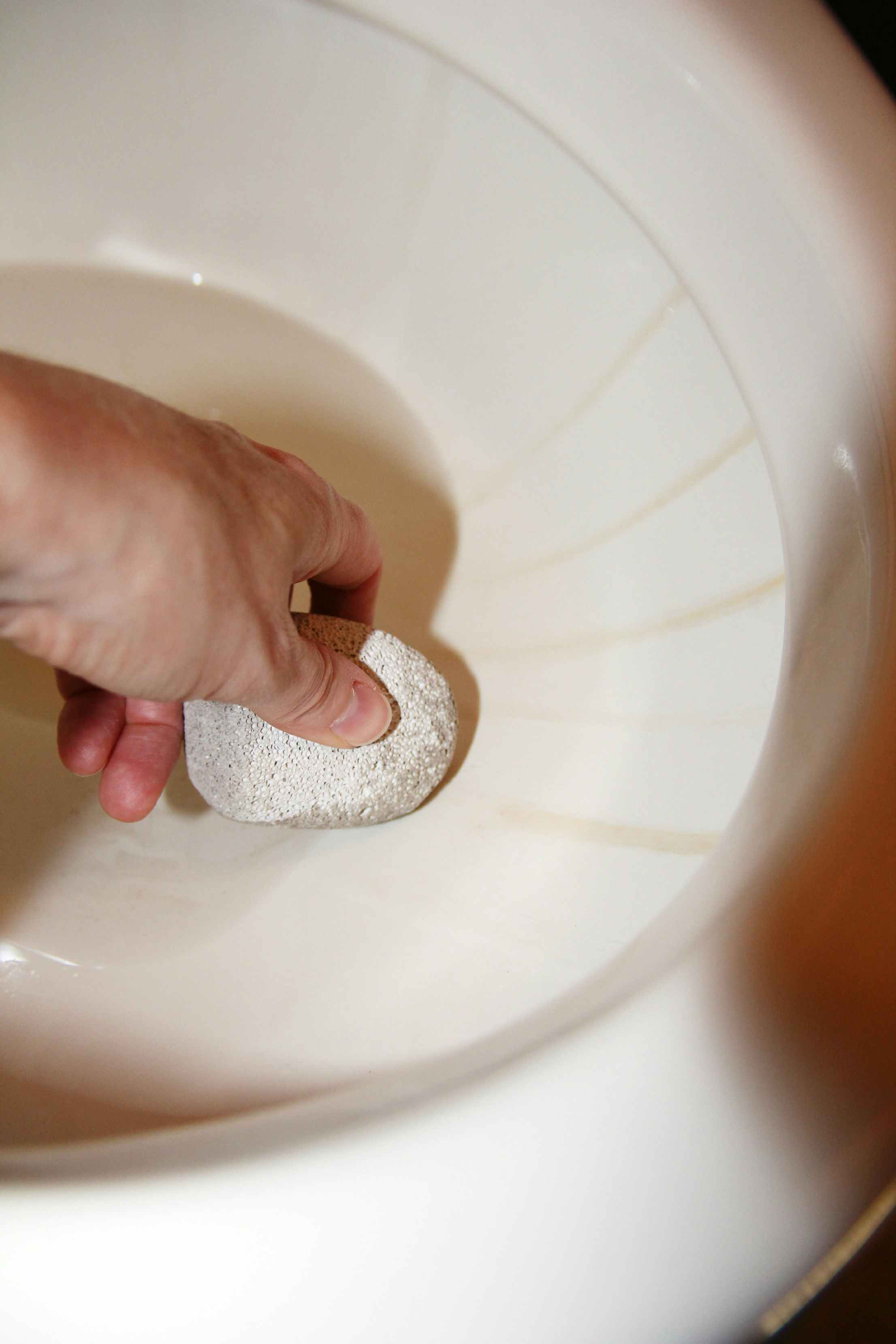 Remove hard water stains in a toilet with a pumice stone.