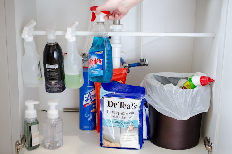 spray bottles hanging from tension rod