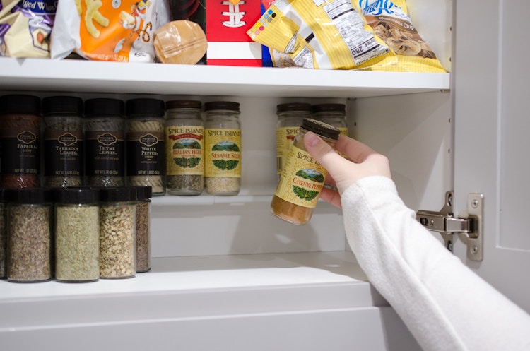 use a tension rod as a small shelf to hold spices