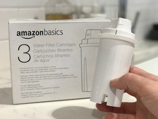 A person holding an AmazonBasics Brita water filter.