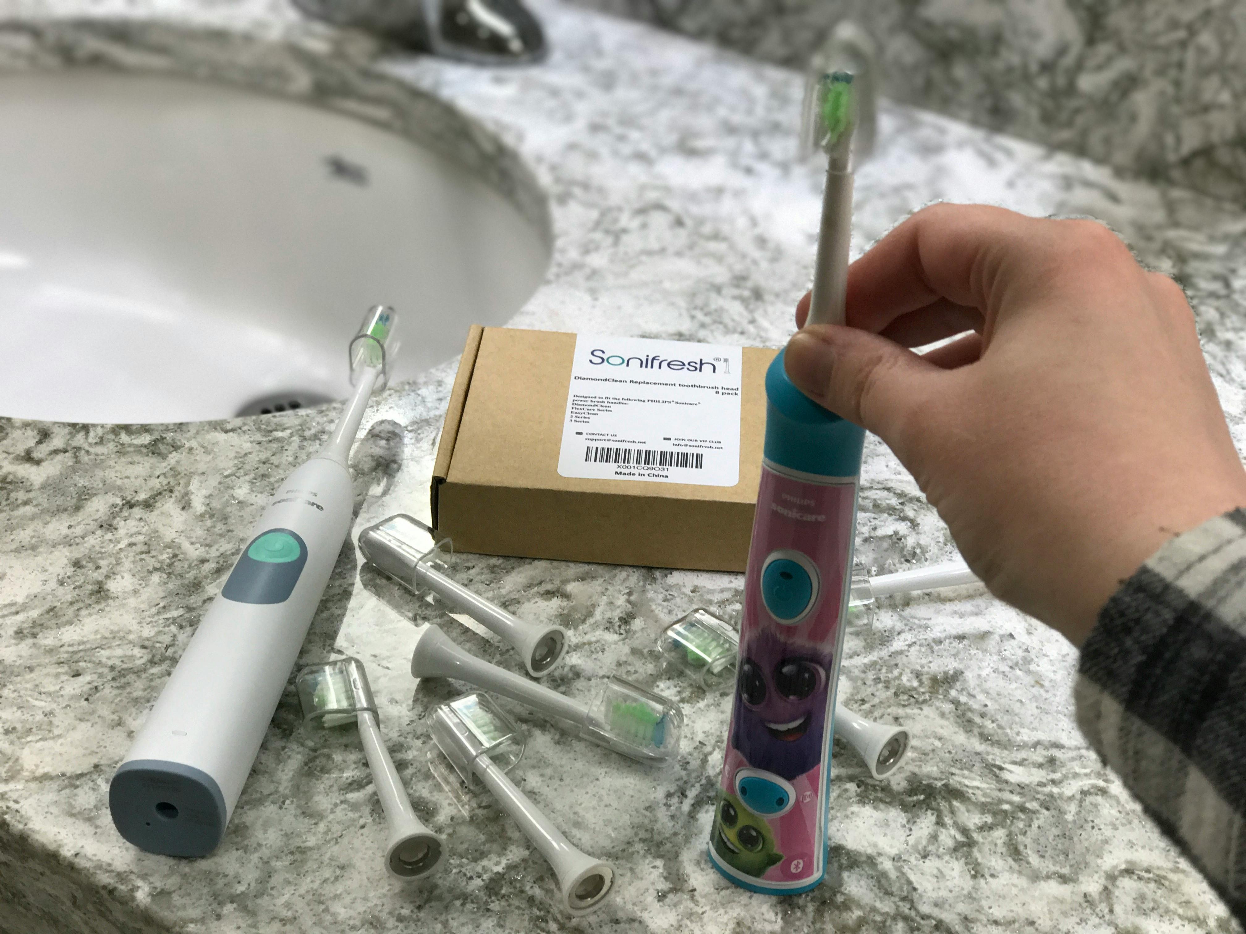 A person holding a Sonicare toothbrush at a sink.