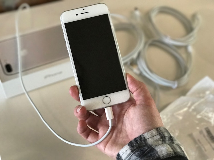 A person holding an iphone wthat's charging.