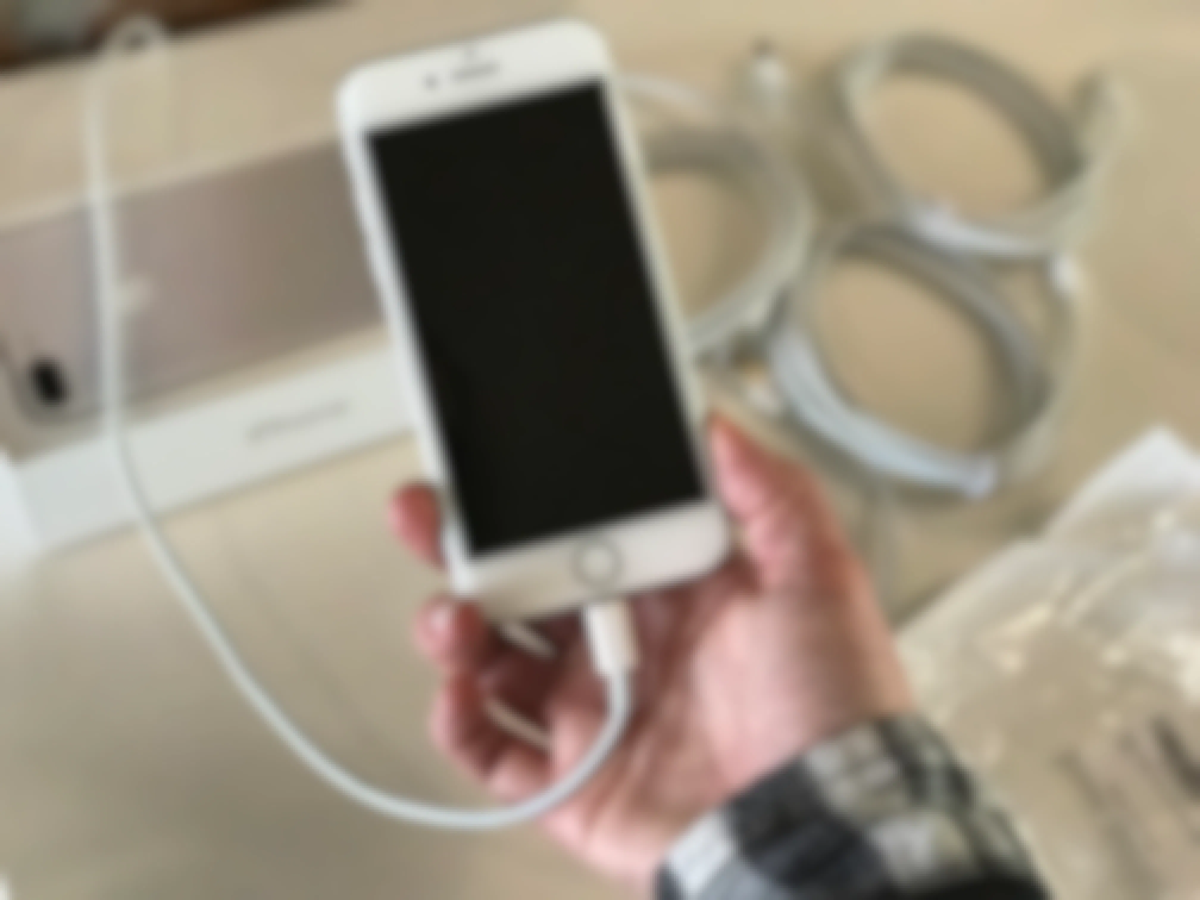 A person holding an iphone wthat's charging.