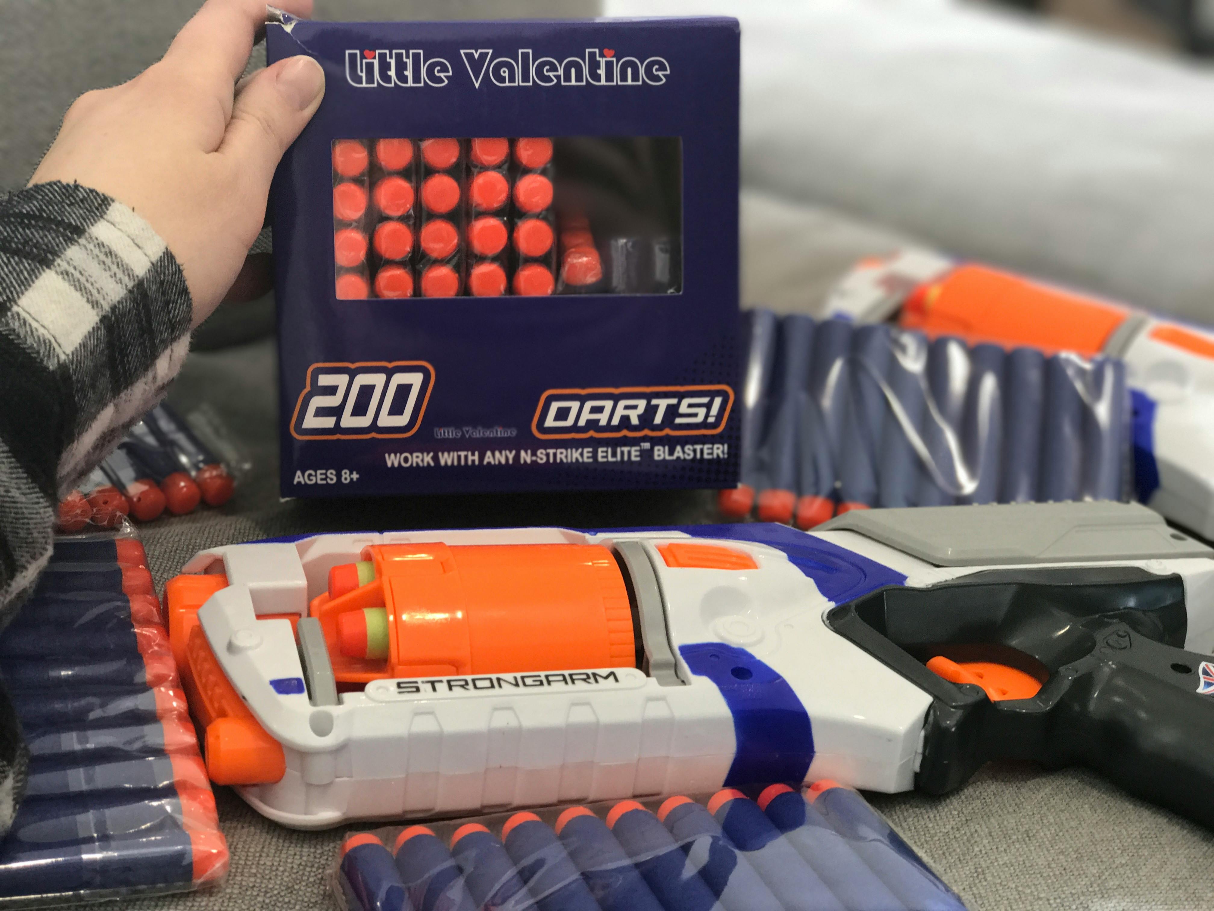 A person holding a package of generic Nerf guns bullets.