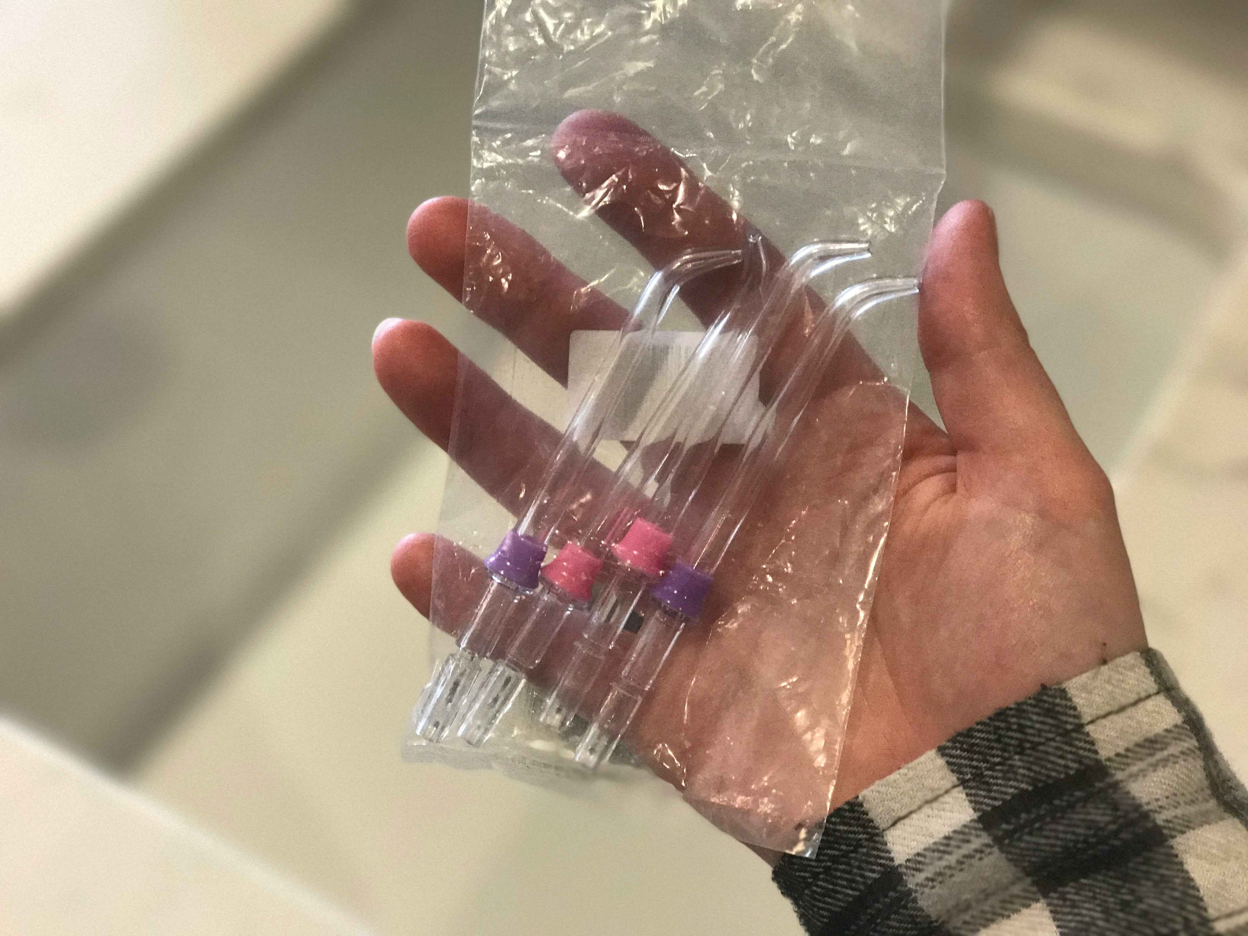 A person holding a package of Waterpik oral flossers.