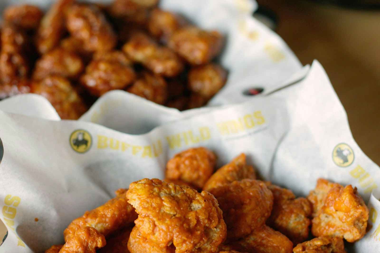 Two baskets of Buffalo Wild Wings boneless wings sitting next to each other.