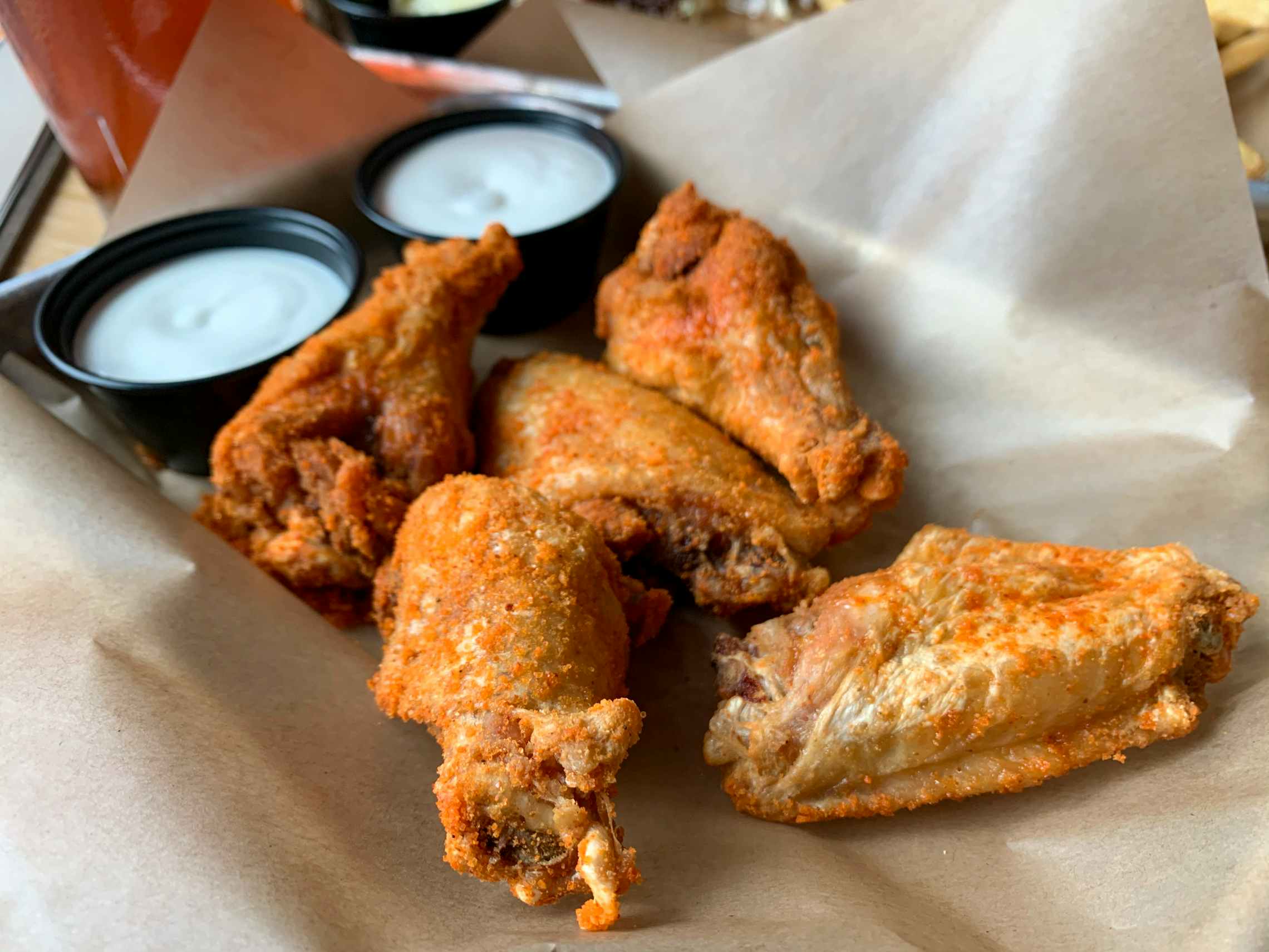 A platter of 5 dry-rub seasoned Buffalo Wild Wings bone-in wings with two dipping cups.