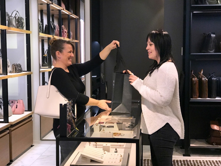 woman checking out at the counter after purchasing a bag in the coach store