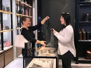 woman checking out at the counter after purchasing a bag in the coach store