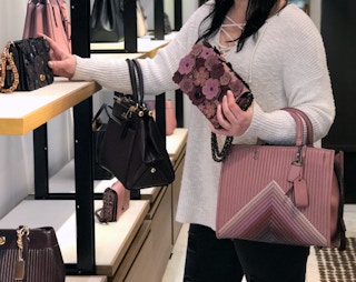 woman shopping for a variety of authentic coach bags inside a coach store