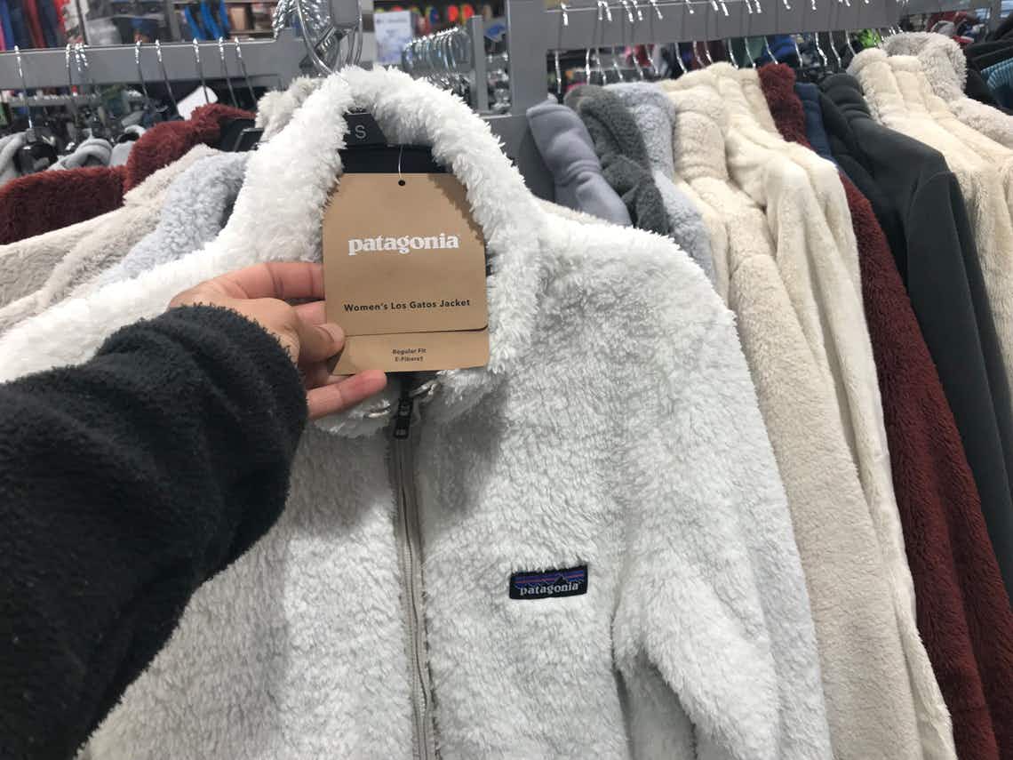 a woman's hand holding the Patagonia tag on a Patagonia fleece zip up at dick's sporting goods
