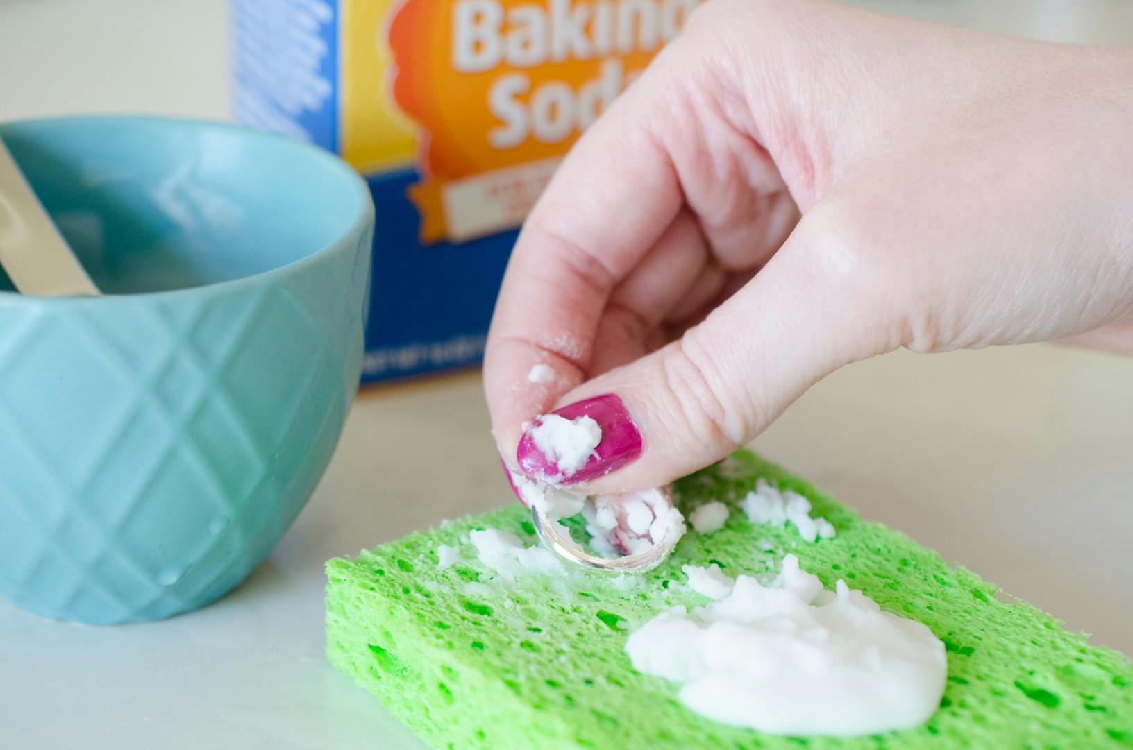 Someone placing a ring on a sponge with baking soda 