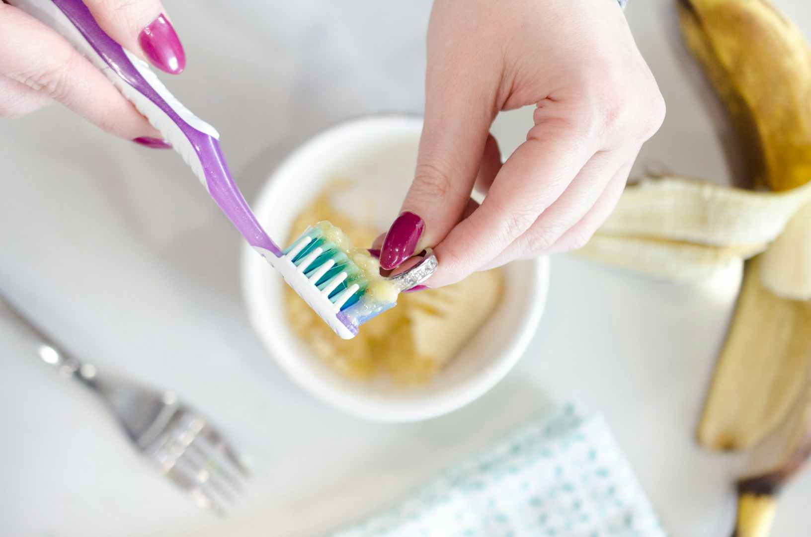Person using a toothbrush to clean a ring with a banana on the counter 