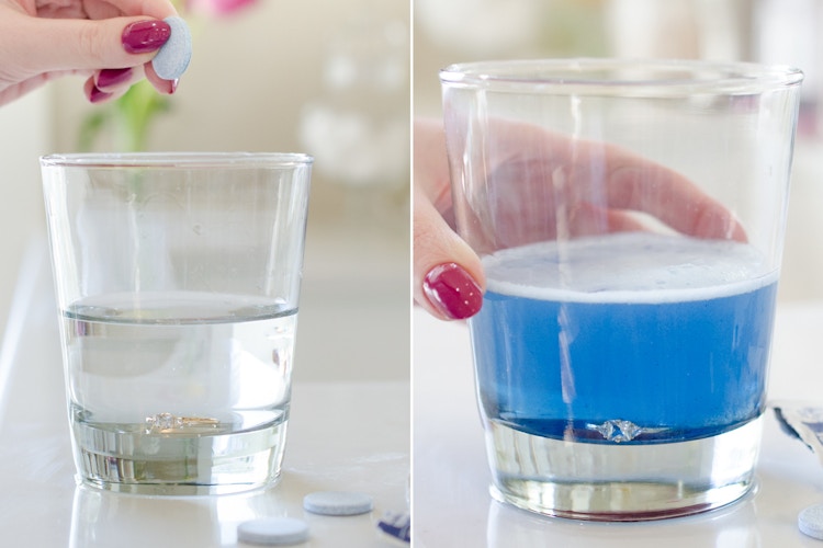 Person placing a denture tablet in a glass with a ring at the bottom