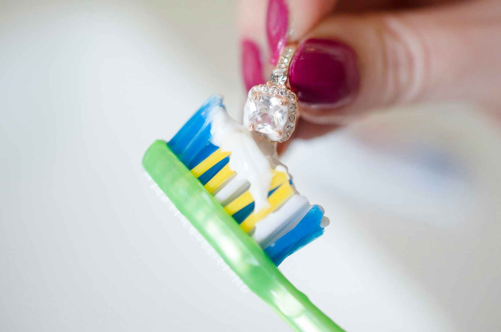 Someone using a toothbrush to clean a diamond ring
