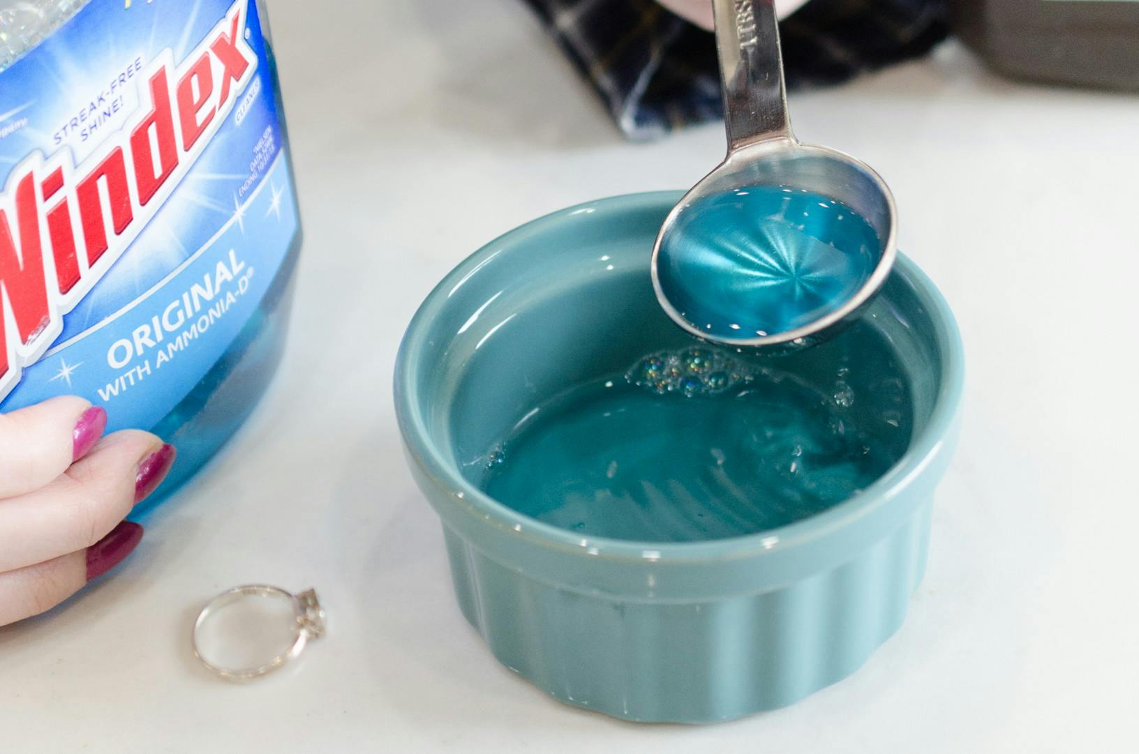 A bowl with blue Windex solution next to a ring