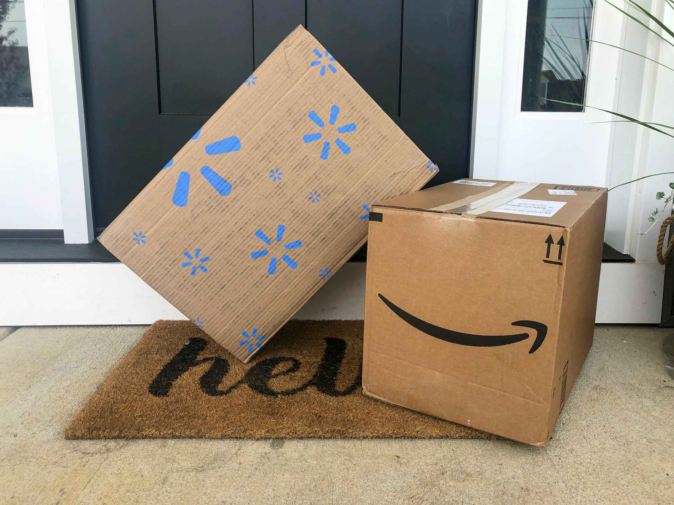 An Amazon and Walmart delivery box sitting on a front doorstep.