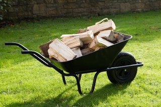 A wheelbarrow filled with firewood in a yard