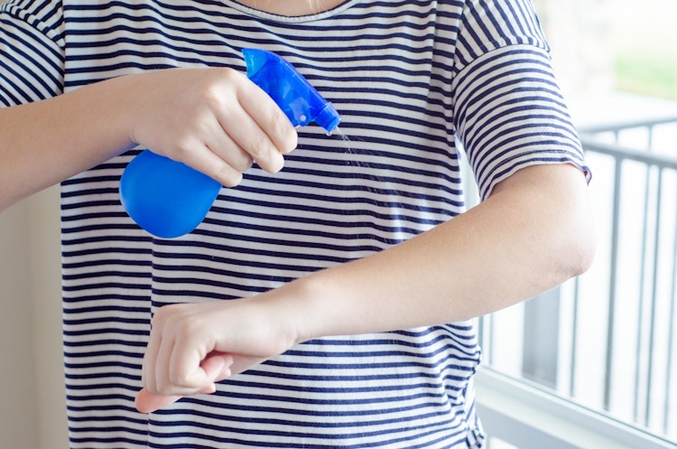 Person spraying natural bug repellent solution onto her arm