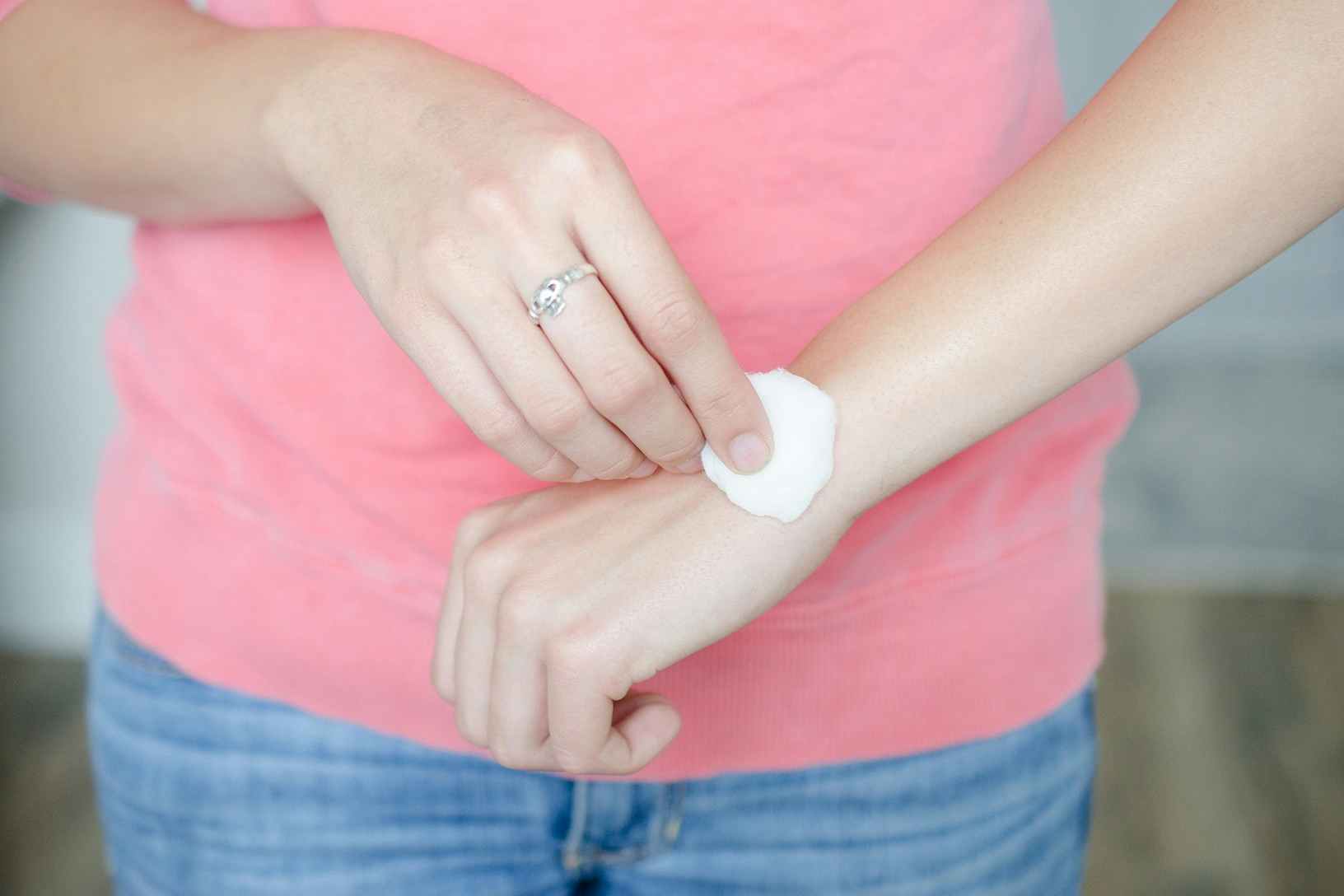 A person rubbing a cotton ball on their wrist.