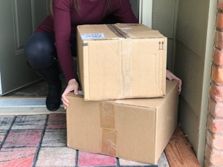 woman takes boxes off front porch