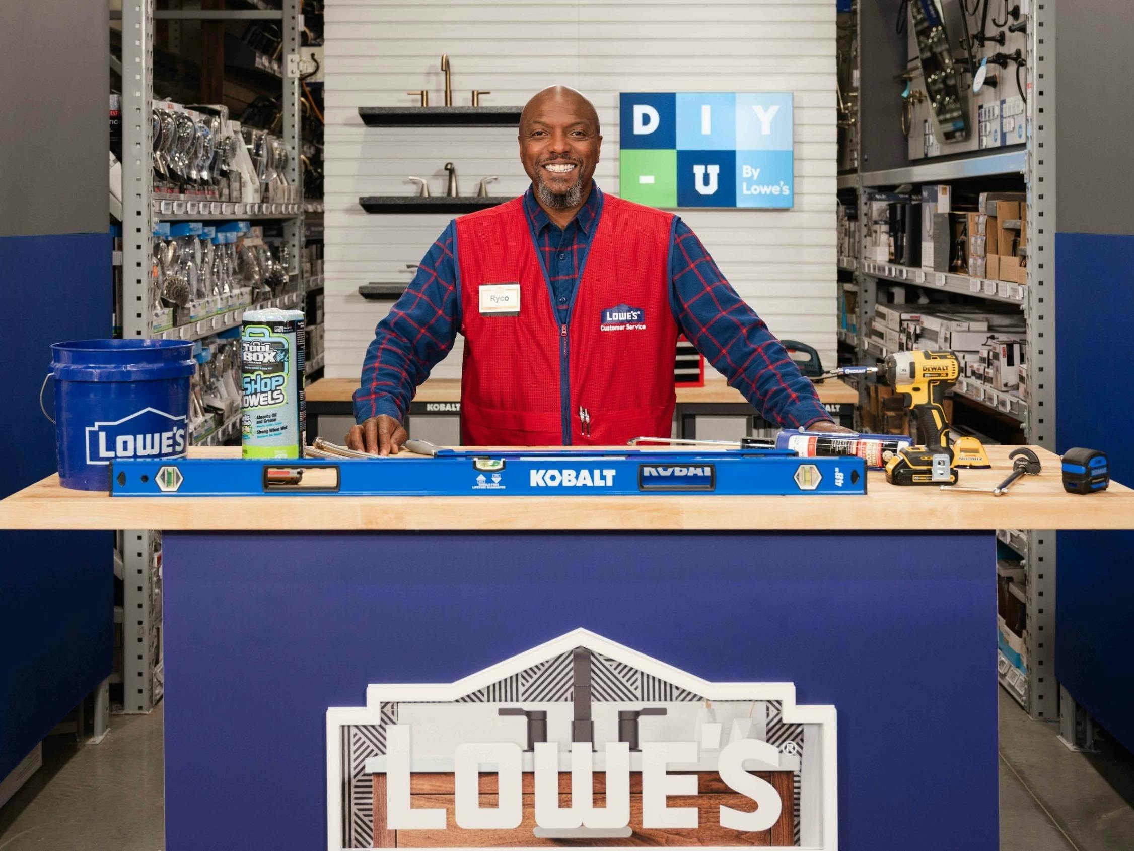 A Lowe's DIY-U instructor standing at a workbench with a DIY-U sign behind him