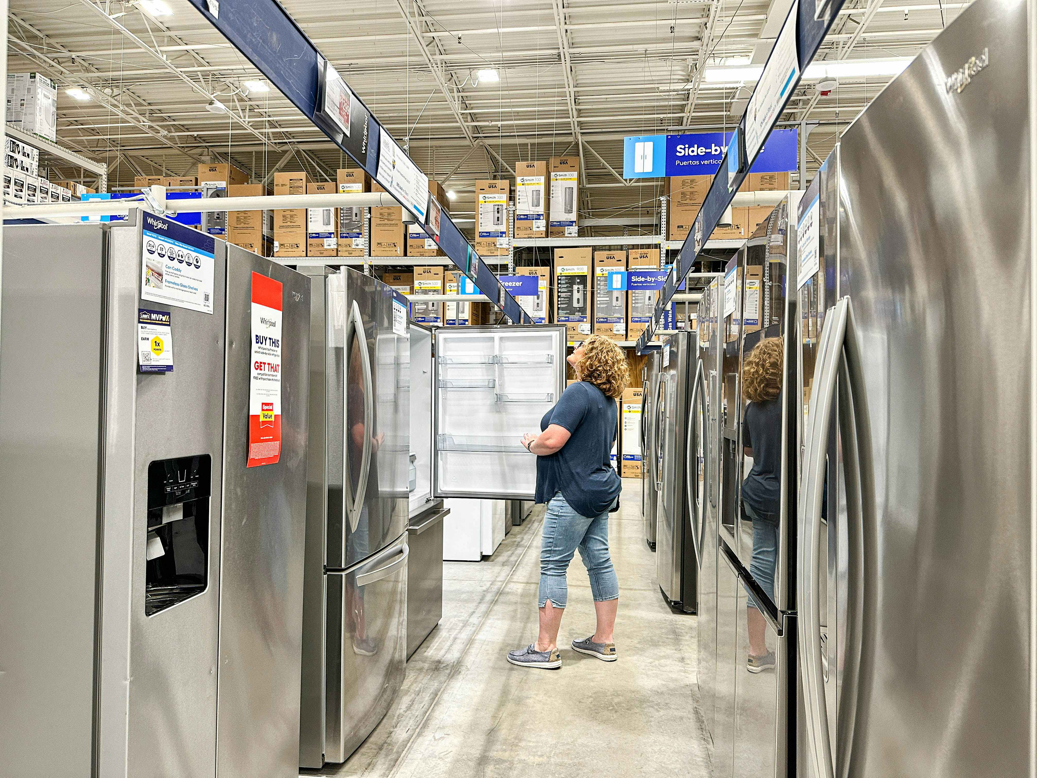 a woman opening a refrigerator in the appliances section at the Lowe's store