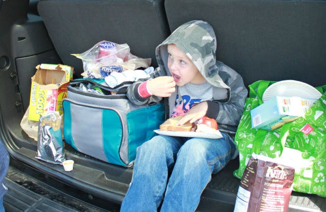 A child eating food while sitting inside the back of a vehicle.