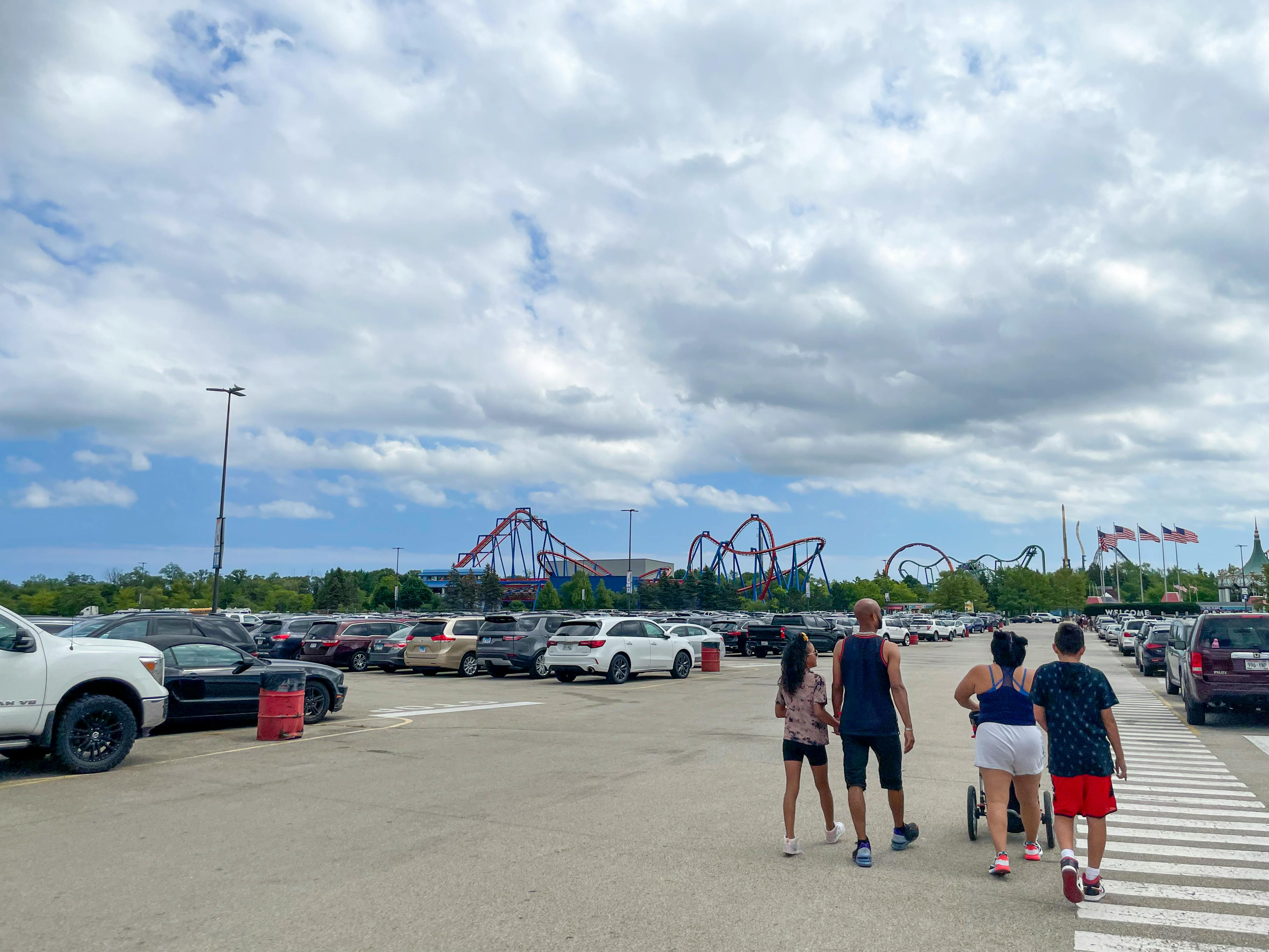 A group of people in a Six Flags amusement park parking lot walking towards the park