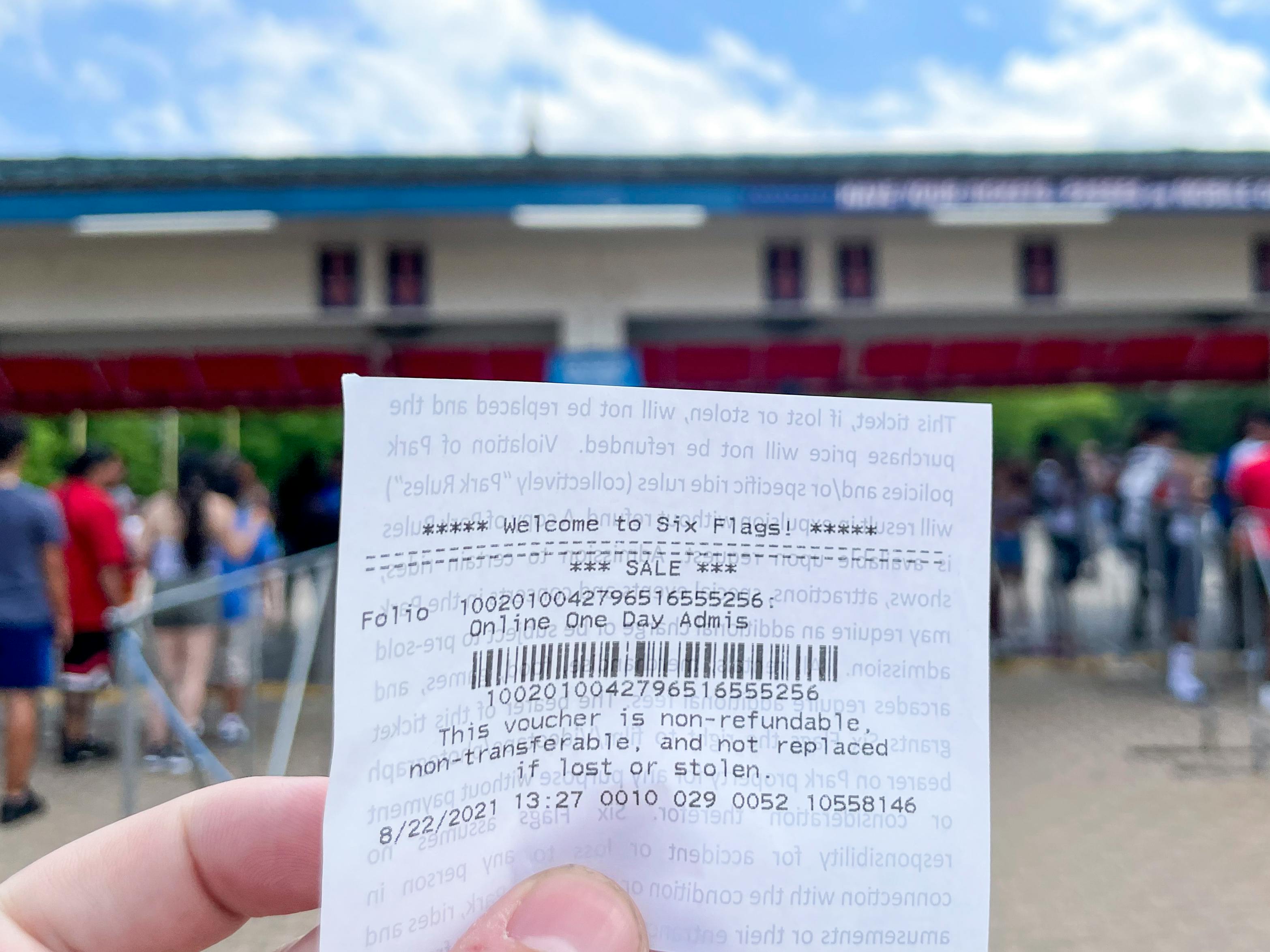 A Six Flags ticket held in front of the amusement park entrance