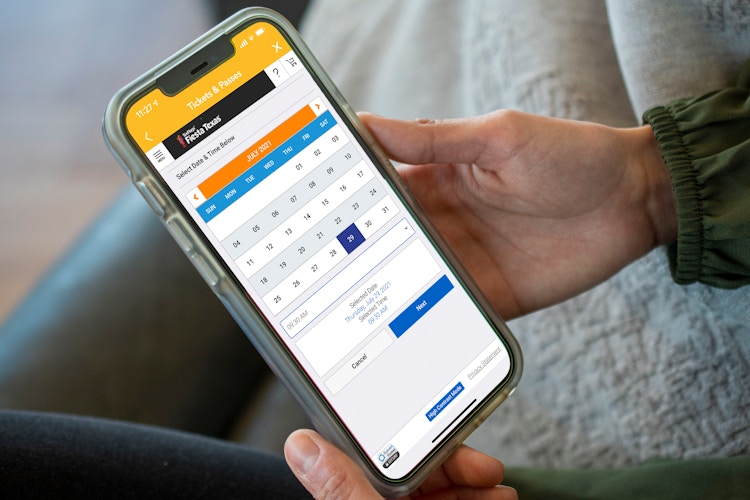 A person selecting a date on the SixFlags app.