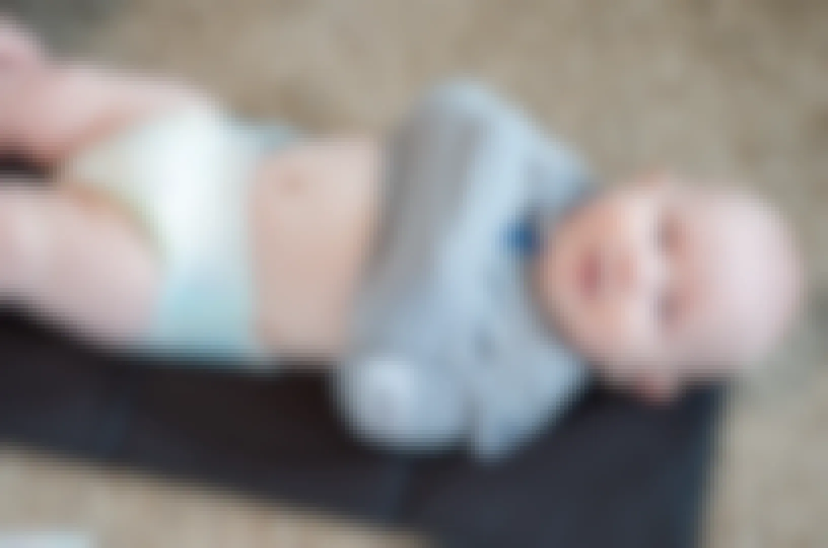baby on diaper-changing mat with arms tucked in onesie