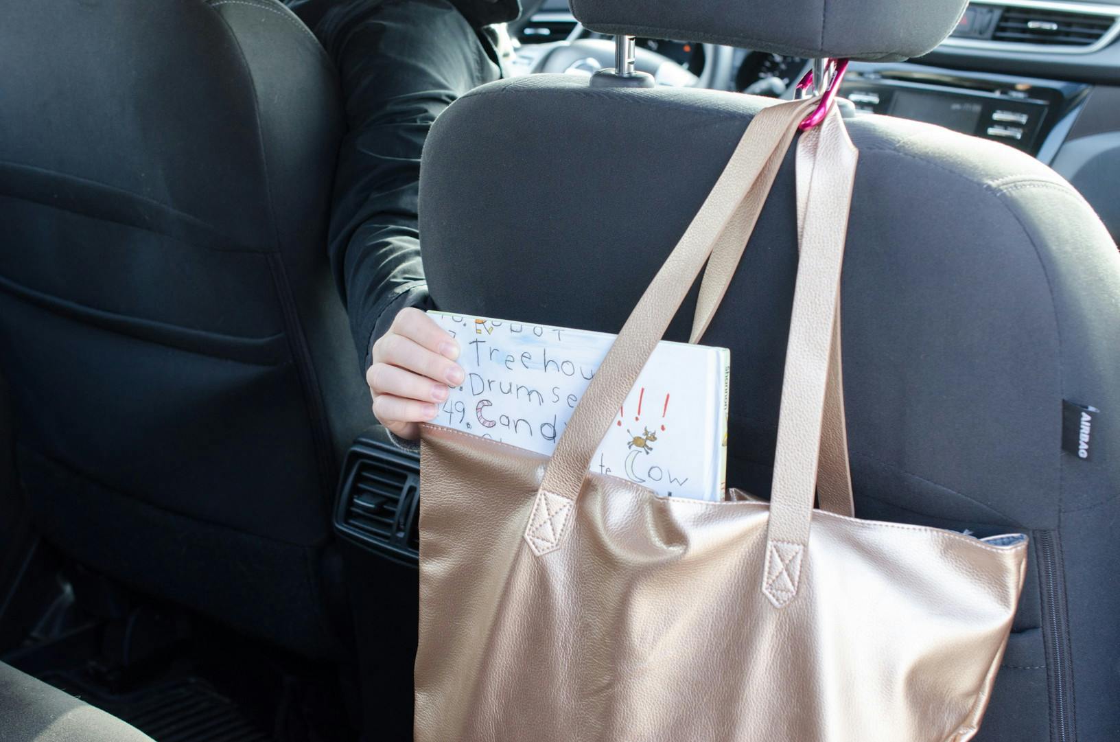someone putting a baby book in a tote bag on the back of a car seat