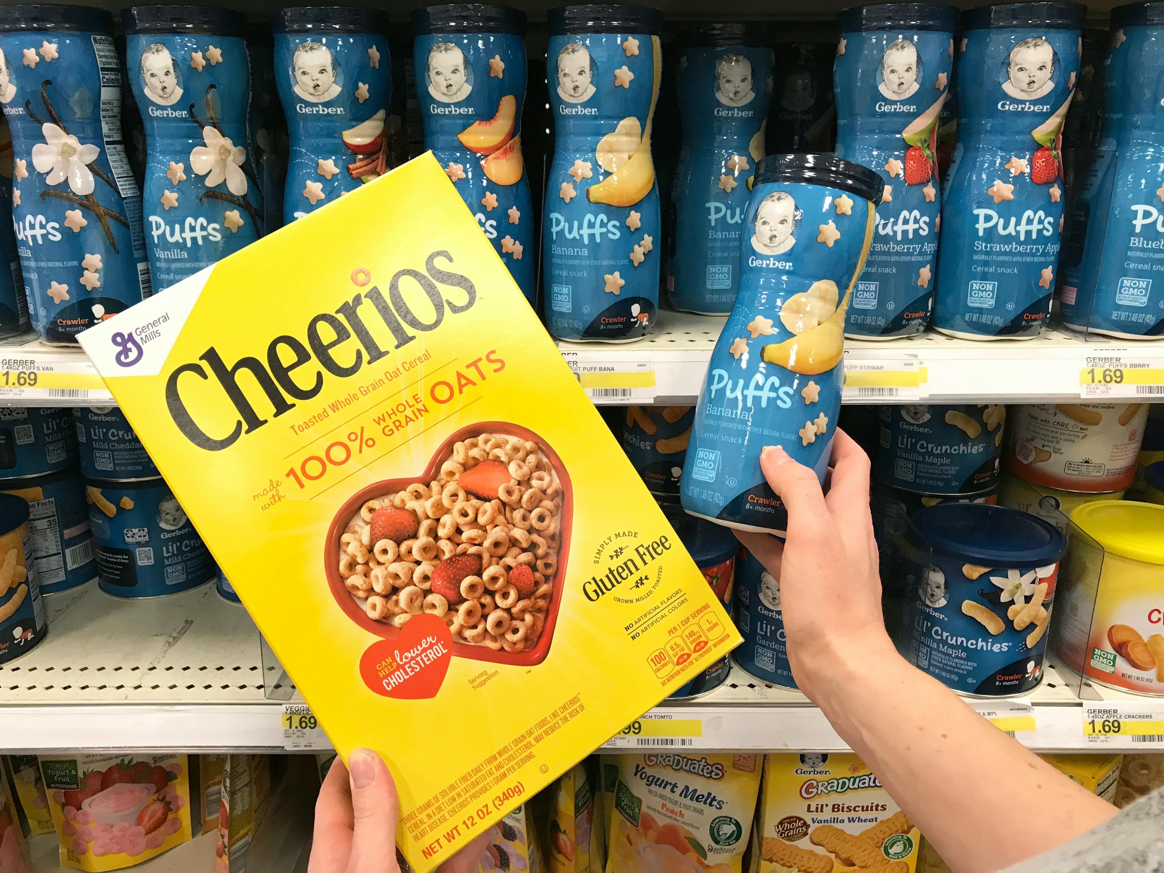 someone holding gerber puffs next to cheerios