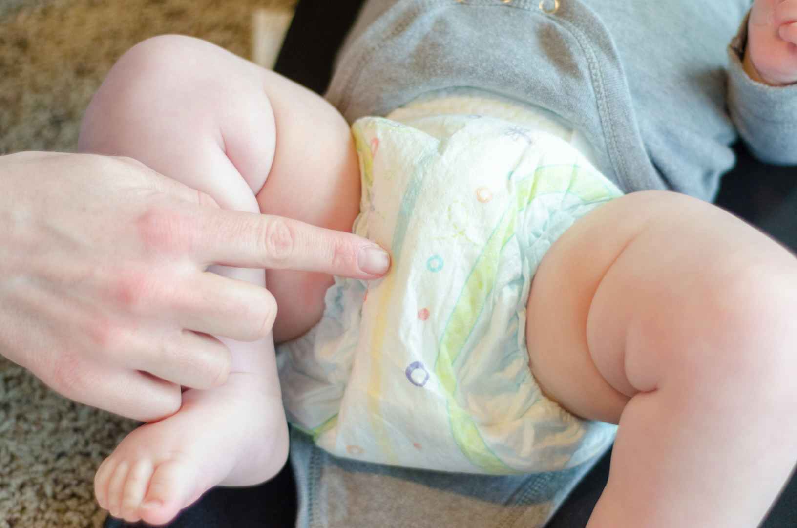pointing to wet indicator line on baby's diaper