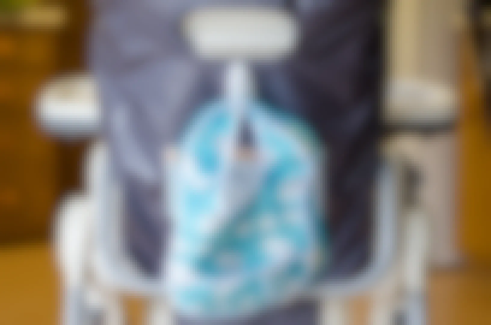 bib hanging from command hook on the back of a high chair