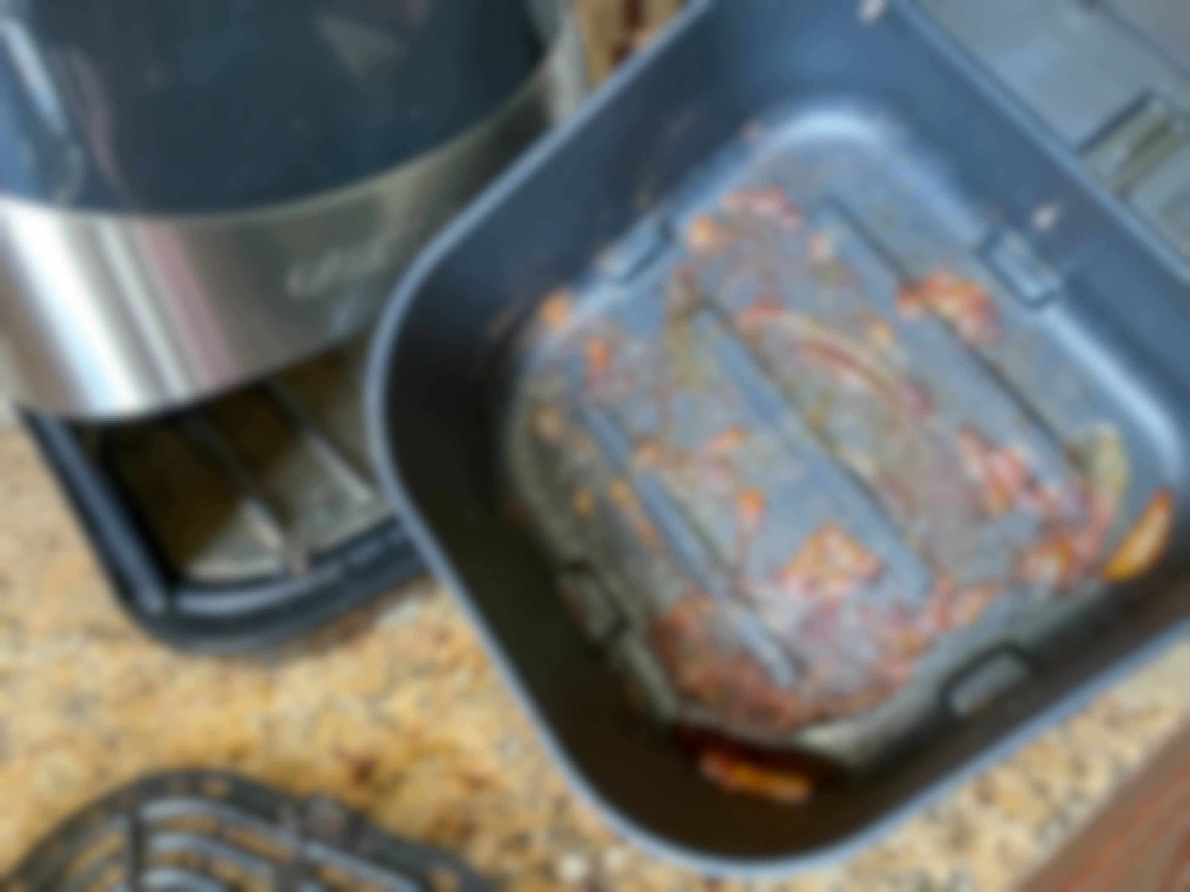 An air fryer with oil and food caked on the bottom of the pan