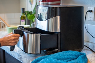 Someone taking the tray out of an air fryer