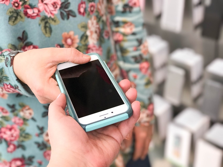 A woman handing an iphone to another person in the apple store. 