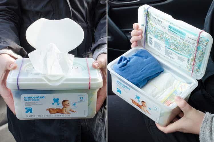 A person holding a baby wipe container with extra diapers and baby clothes in it.