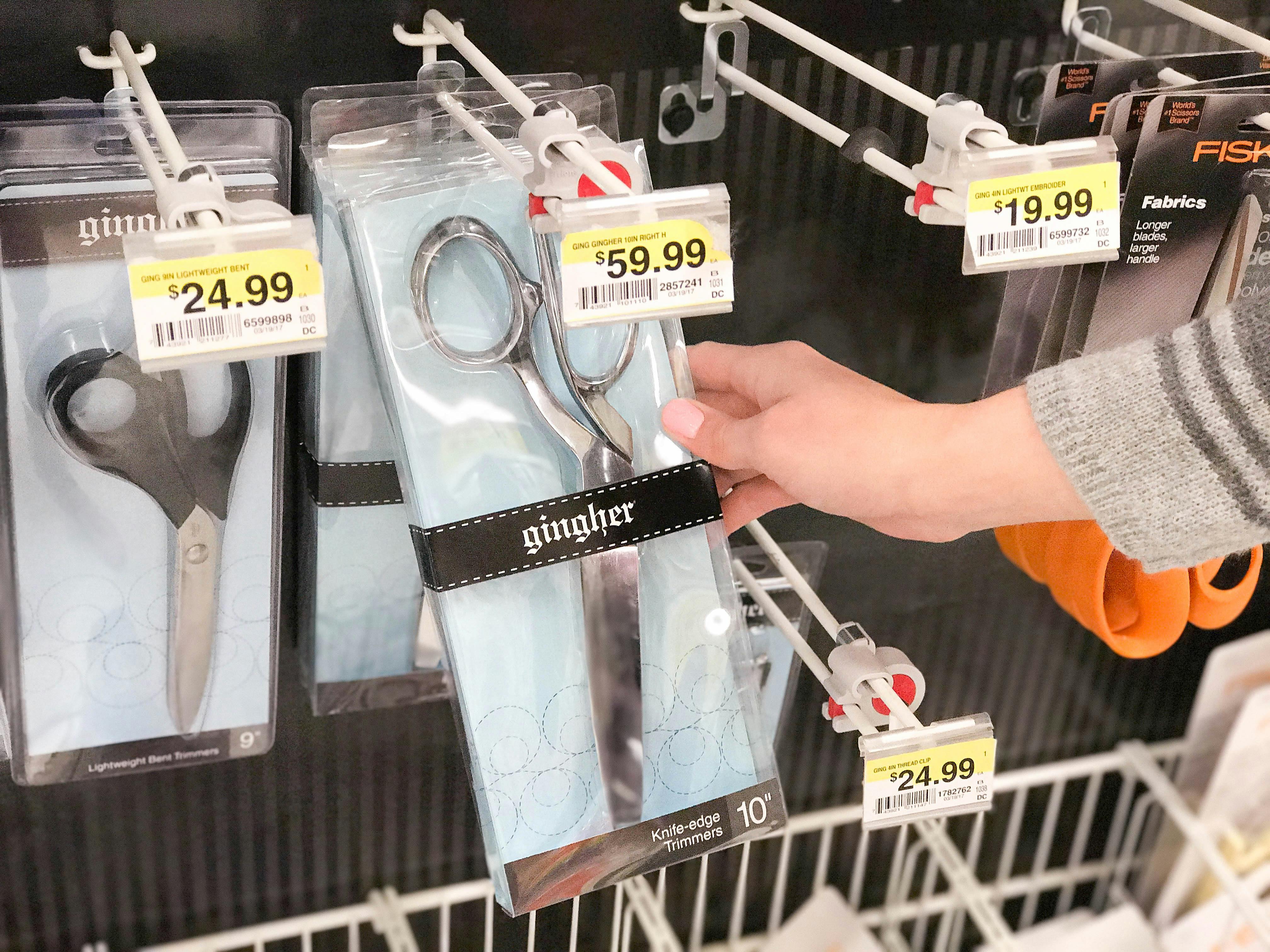hand holding a pair of gingher scissors in front of more more scissors