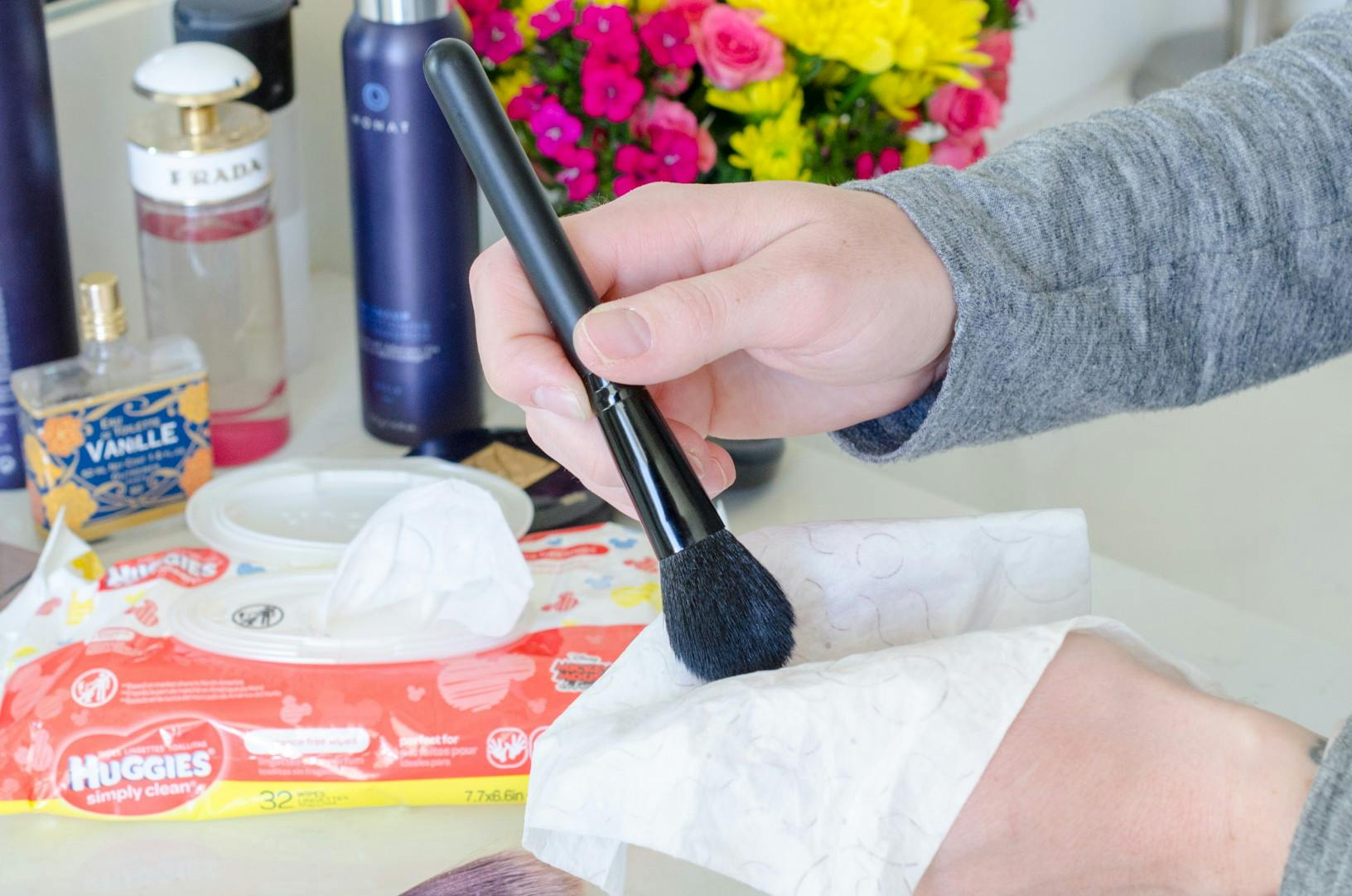 A person using a baby wipe to clean a makeup brush.