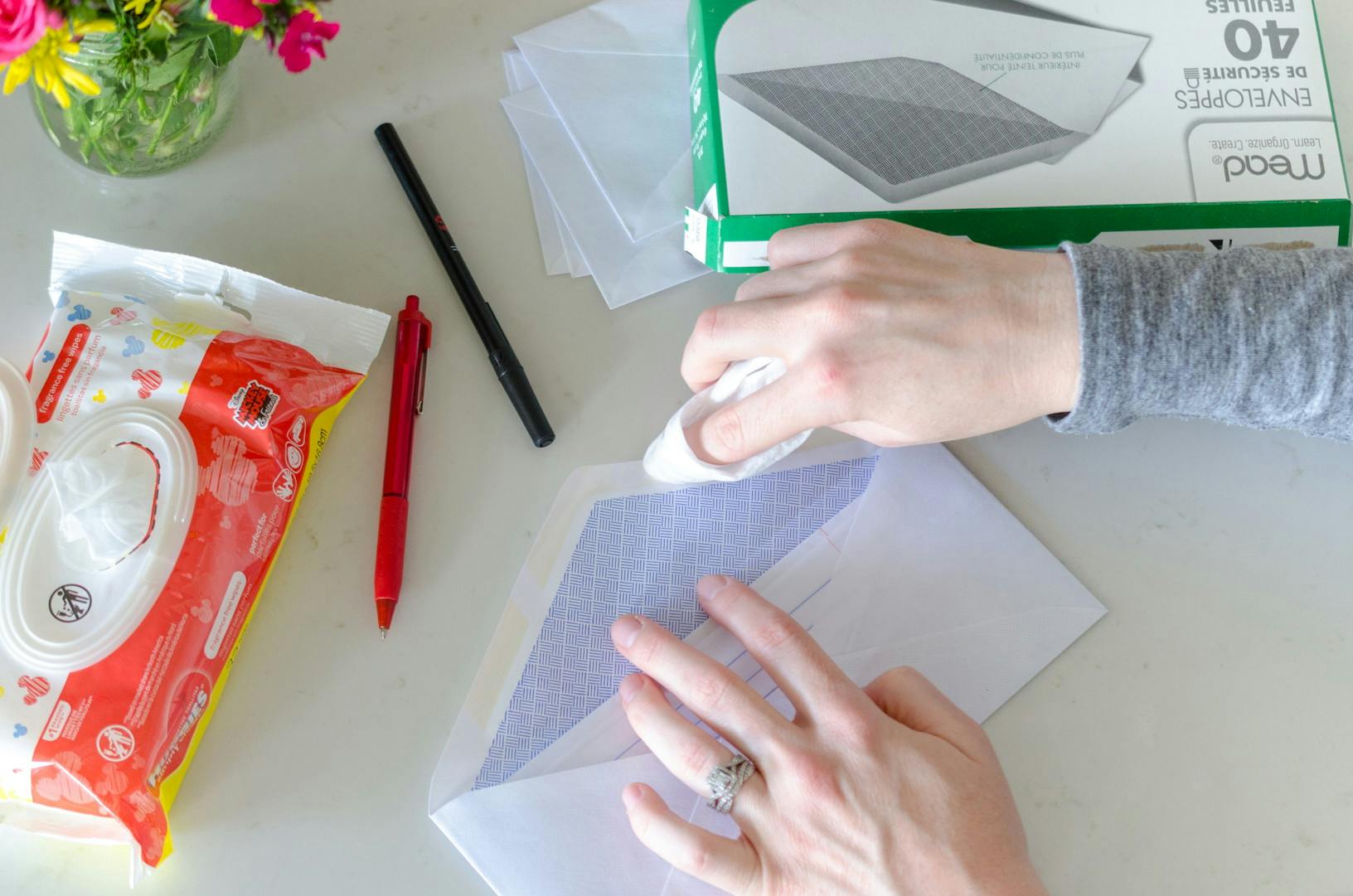 A person using a baby wipe to moisten and envelope.