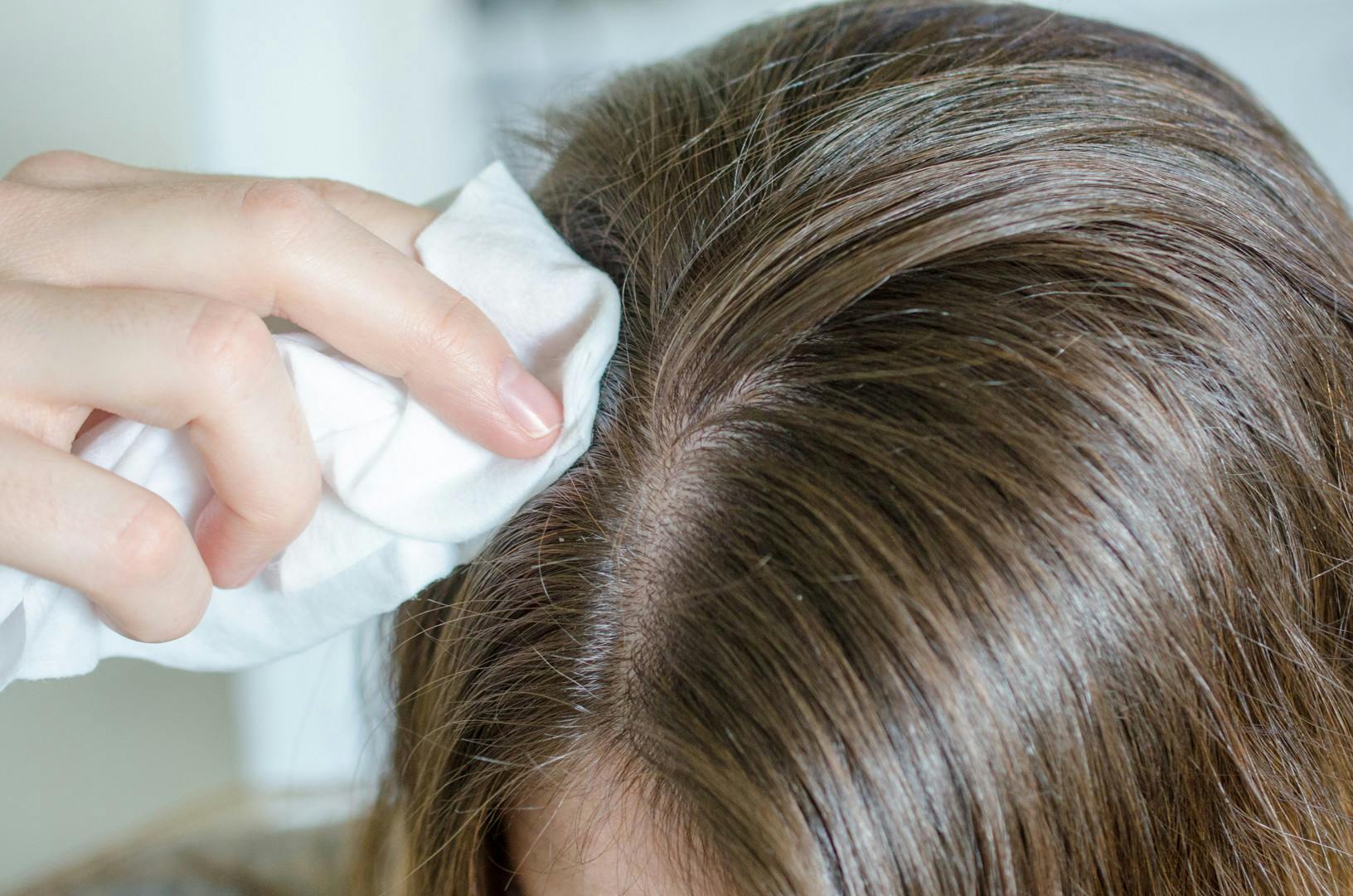 A person using a baby wipe to wet their little hairs on top of their head.