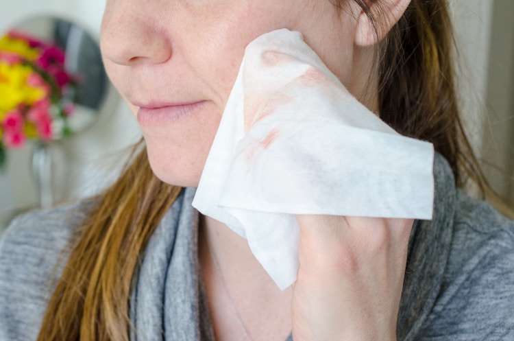 Woman removing makeup from her face with a baby wipe.