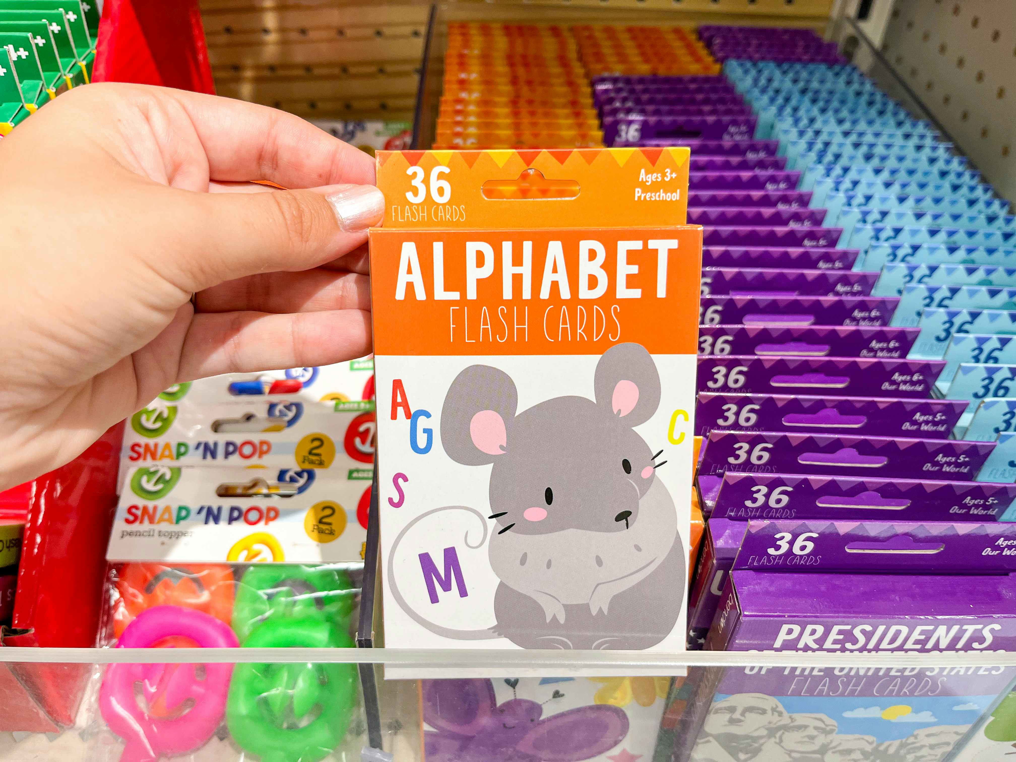 A woman's hand holding up a 36-pack of Alphabet flashcards at Target
