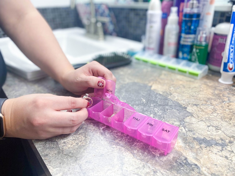 woman putting jewelry in pill organizer